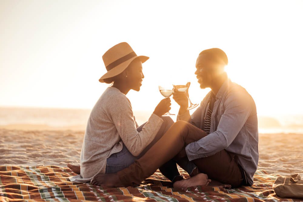 A couple enjoying drinks on the beach during their Sanibel Island honeymoon.